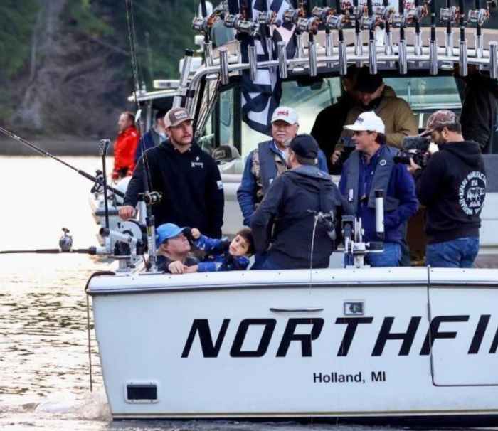 JD Vance sitting at the back of a boat next to his 4 year old son